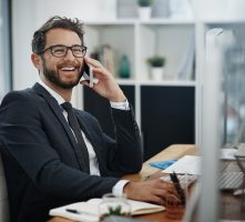 Shot of a young businessman talking on a cellphone while working in an office.