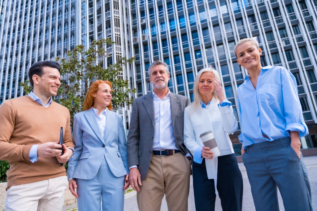 Group of coworkers walking going to work outdoors in a corporate office area, commercial area